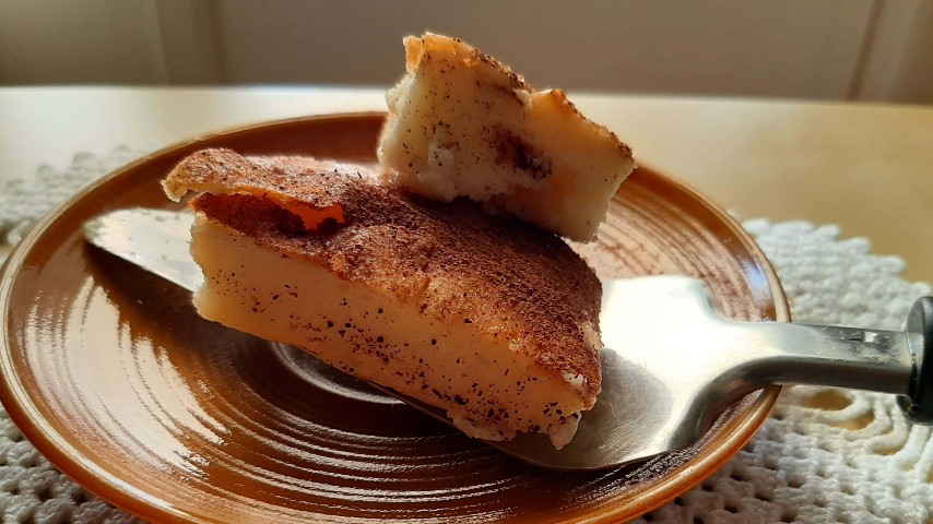 A piece of "Grandma's" Greek traditional galatopita on a ceramic plate with a spatula