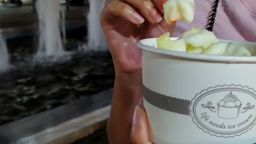 Τρώγοντας το ice cream roll βανίλια με μάνγκο μπροστά από ένα σιντριβάνι