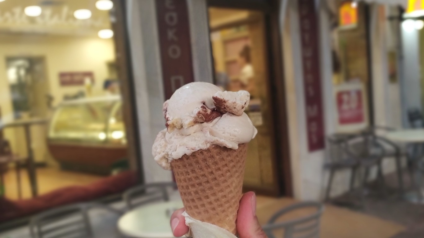 Hand holding a cone with a scoop of the tiramisu flavor from Arte Italiana, in front of the store